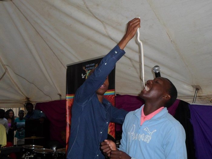 Self-styled South African prophet Penuel Mnguni, 24 (l) feeds a snake to one of his congregants.