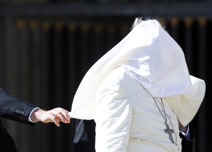 A gust of wind blows Pope Francis' mantle as he leaves at the end of his weekly audience in Saint Peter's Square at the Vatican, October 22, 2014.