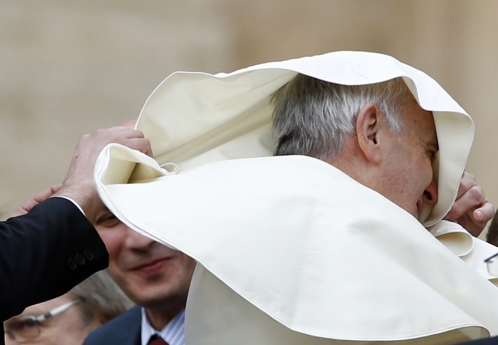 A gust of wind blows Pope Francis' mantle as he leaves at the end of his weekly audience in Saint Peter's Square at the Vatican, November 5, 2014.