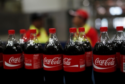 Workers stand near bottles of Coca-Cola on a newly inaugurated production line at the Cikedokan Plant in Bekasi, West Java near Jakarta, March 31, 2015. The Coca-Cola company inaugurated two new production lines as part of an investment package worth some $500 million to accelerate growth in the Indonesian market.