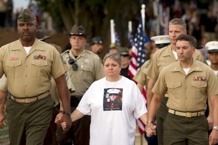 Cathy Wells, the mother of Marine Lance Cpl. Squire K. 'Skip' Wells, who was one of the five military servicemen slain last week in Chattanooga in a domestic terror attack, is escorted by members of the U.S. military at her son's vigil at Sprayberry High School in Marietta, Georgia July 21, 2015. Wells, 21, a reservist, was the youngest victim of an attack being investigated as an act of domestic terrorism. He was killed last Thursday when authorities say Mohammod Youssuf Abdulazeez opened fire at a Naval Reserve Center in Chattanooga, Tennessee, slaying Wells and three other Marines. A sailor later died of his wounds.