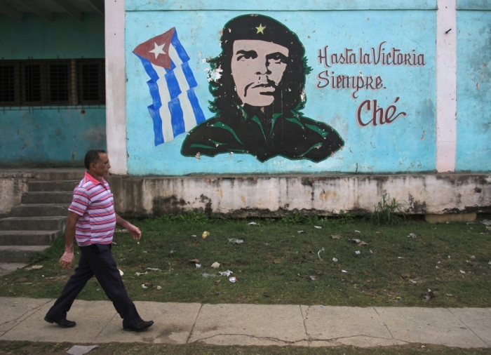 A man walks past near an image of revolutionary hero Ernesto 'Che' Guevara in Havana December 27, 2014. Cuba's most prominent dissidents say they have been kept in the dark by U.S. officials over a list of 53 political prisoners who will be released from jail as part of a deal to end decades of hostility between the United States and Cuba. Picture taken December 27, 2014.