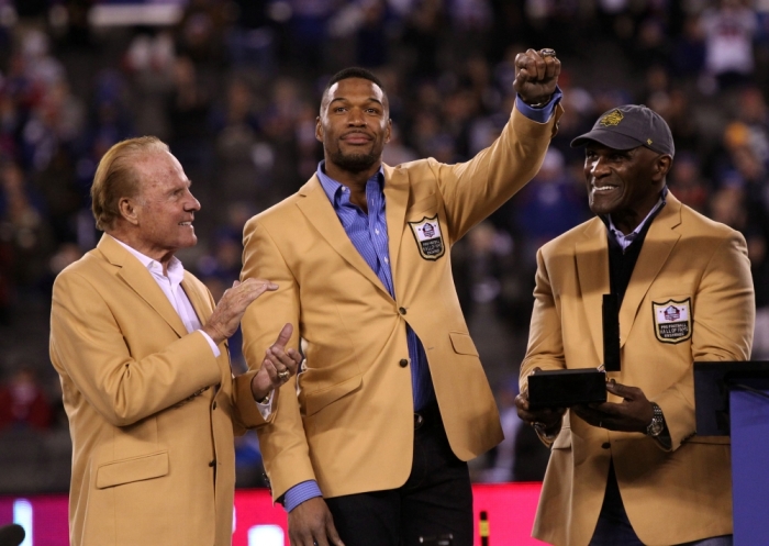 Michael Strahan (Center) receives his NFL Hall of Fame ring from Harry Carson and Frank Gifford during half time ceremony at MetLife Stadium, November 3, 2014, in East Rutherford, New Jersey.