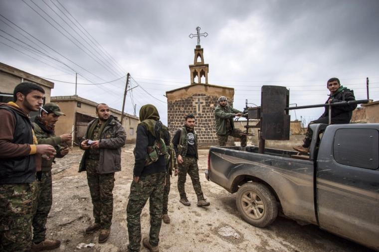 Fighters of the Kurdish People's Protection Units (YPG) stand near a pick-up truck mounted with an anti-aircraft weapon in front of a church in the Assyrian village of Tel Jumaa, north of Tel Tamr town February 25, 2015. Kurdish militia pressed an offensive against Islamic State in northeast Syria on Wednesday, cutting one of its supply lines from Iraq, as fears mounted for dozens of Christians abducted by the hardline group. The Assyrian Christians were taken from villages near the town of Tel Tamr, some 20 km (12 miles) to the northwest of the city of Hasaka. There has been no word on their fate. There have been conflicting reports on where the Christians had been taken.