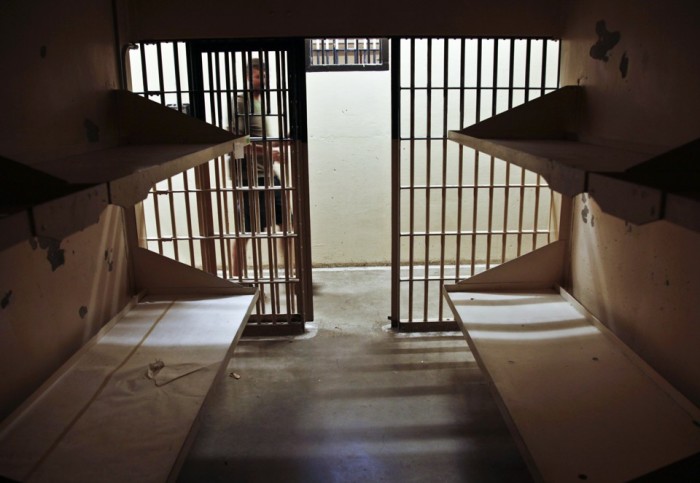 A man walking into a prison cell.