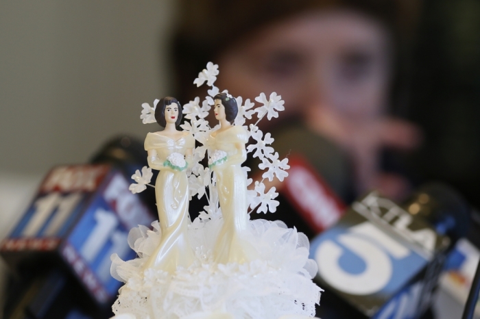 Wedding cake toppers are pictured as Robin Tyler cries in the background at a news conference in Los Angeles, after the United States Supreme court ruled on California's Proposition 8 and the federal Defense of Marriage Act, June 26, 2013.