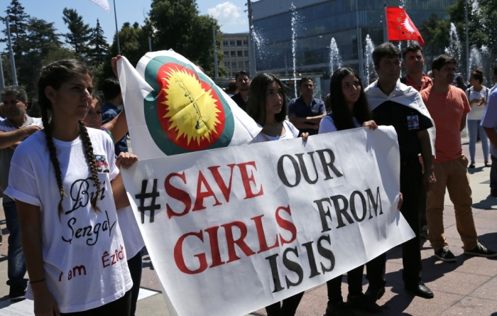 Women hold a banner during a demonstration marking the first anniversary of Islamic State's surge on Yazidis of the town of Sinjar, in front of the United Nations European headquarters in Geneva, Switzerland, August 3, 2015.