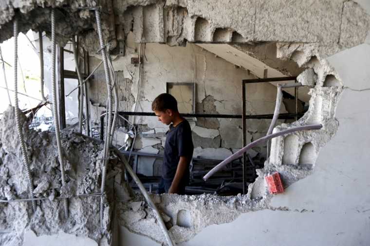 A child inspects a site hit by what activists said was an airstrike by forces loyal to Syria's President Bashar el-Asaad at Arbin town in Damascus countryside, Syria, July 21, 2015.