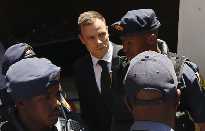 South African Olympic and Paralympic sprinter Oscar Pistorius (C) is escorted to a police van after his sentencing at the North Gauteng High Court in Pretoria October 21, 2014.