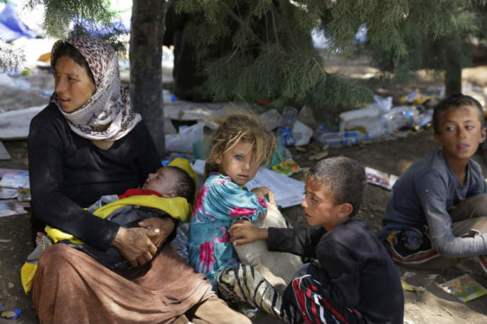 A displaced family from the minority Yazidi sect, fleeing the violence in the Iraqi town of Sinjar, waits for food while resting at the Iraqi-Syrian border crossing in Fishkhabour, Dohuk province on Aug. 13, 2014.