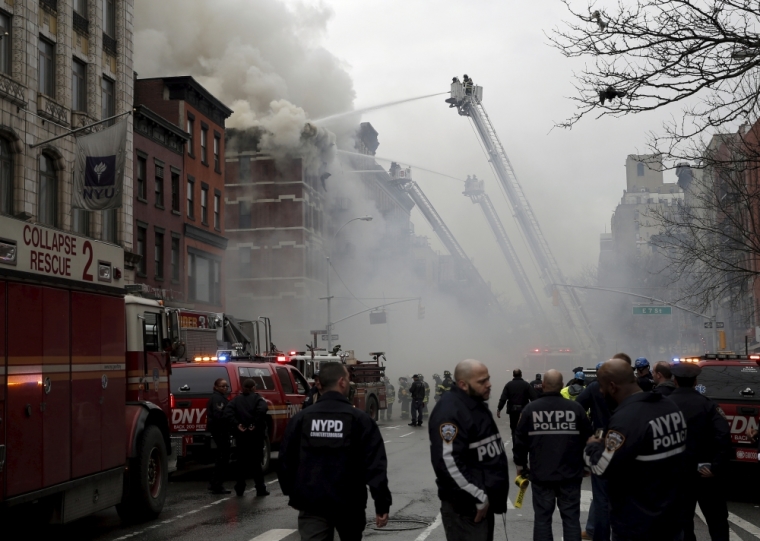 New York City Fire Department firefighters and police stand by as firefighters fight a fire at a residential apartment building in New York City March 26, 2015. The residential apartment building collapsed and was engulfed in flames on Thursday in New York City's East Village neighborhood, critically injuring at least one person, authorities said.
