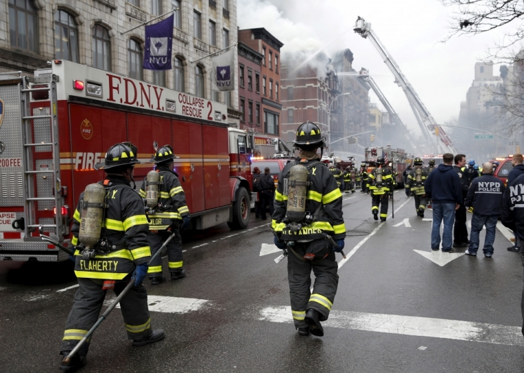 New York City Fire Department firefighters walk on 2nd Avenue towards the site of where a residential apartment was engulfed in flames in New York City, March 26, 2015. The residential apartment building collapsed and was engulfed in flames on Thursday in New York City's East Village neighborhood, critically injuring at least one person, authorities said.