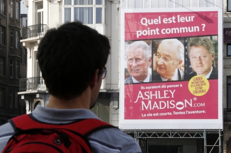 A tourist looks at an advertising campaign by Ashley Madison, a dating website for people who are already in a relationship, showing pictures of (L-R) Britain's Prince Charles, Belgium's King Albert II and former U.S. President Bill Clinton in central Brussels October 24, 2012. The poster reads