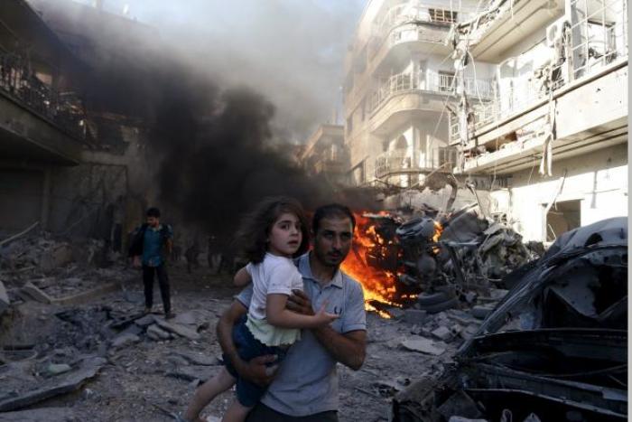 A man carries a girl as they rush away from a site hit by what activists said were airstrikes by forces loyal to Syria's President Bashar al-Assad in the Douma neighborhood of Damascus, Syria August 24, 2015.