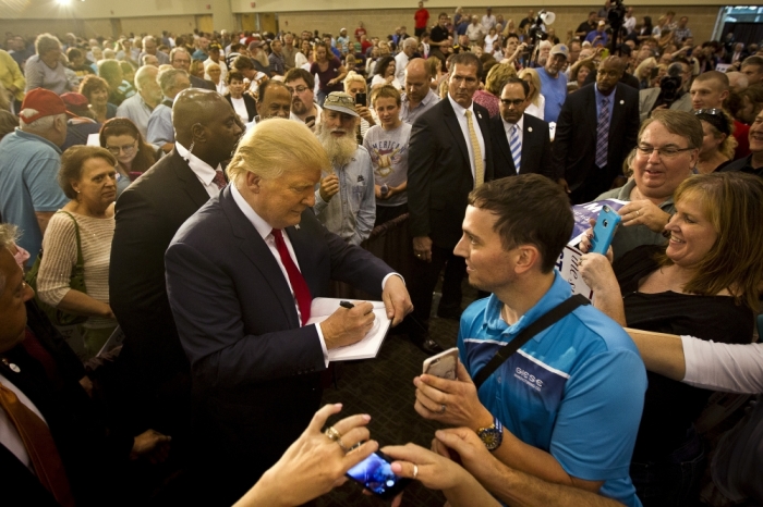Republican Presidential candidate Donald Trump signs an autograph for a supporter during his 'Make America Great Again Rally' at the Grand River Center in Dubuque, Iowa, August 25, 2015.