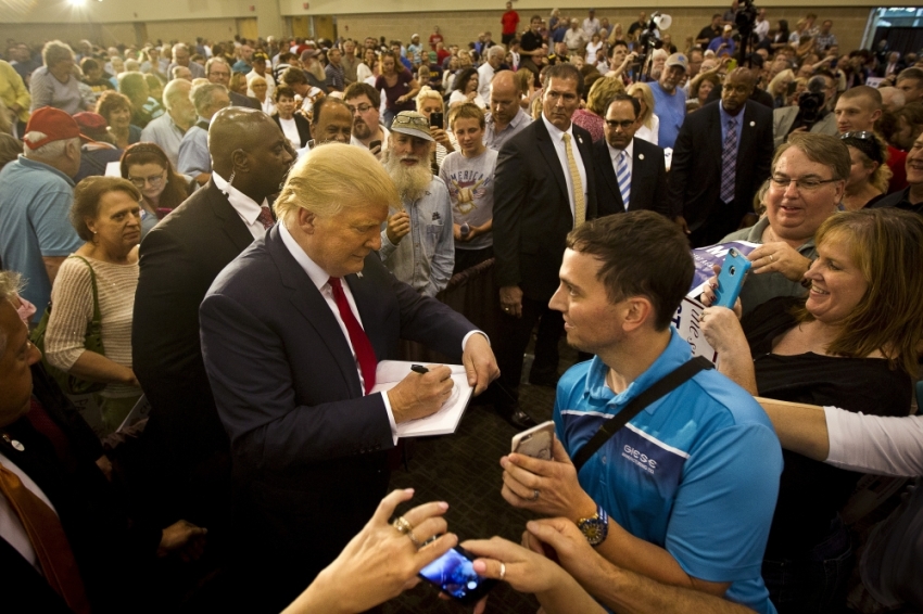 Republican Presidential candidate Donald Trump signs an autograph for a supporter during his "Make America Great Again Rally" at the Grand River Center in Dubuque, Iowa, August 25, 2015.
