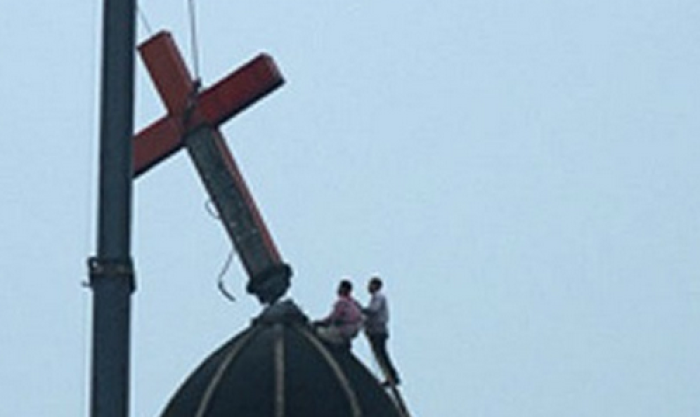 Government workers take down a giant cross on top of a Christian church in China in this undated image.