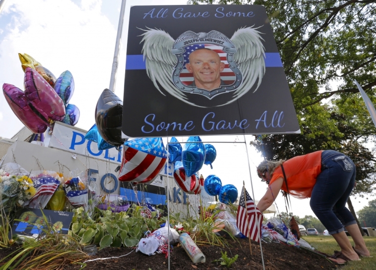 A woman lays flowers at a vigil for slain Fox Lake Police Lieutenant Charles Joseph Gliniewicz in Fox Lake, Illinois, United States, September 2, 2015. Authorities in northern Illinois expanded their search for three suspects in the fatal shooting of a 30-year police officer as local schools were closed on Wednesday and vigils for the officer were planned. Gliniewicz, a father of four boys and a decorated officer, was known around the village as 'G.I. Joe' and was dedicated to Fox Lake and his fellow officers, Mayor Donny Schmit said.