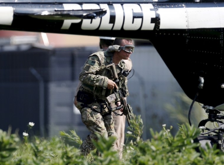 An armed police officer walks throughs a field as authorities take part in a manhunt in Fox Lake, Illinois, United States, September 1, 2015. Police with dogs and helicopters are searching woods and swampy areas north of Chicago for three armed suspects after a police officer was shot dead on Tuesday in the suburb of Fox Lake, a local law enforcement official said.