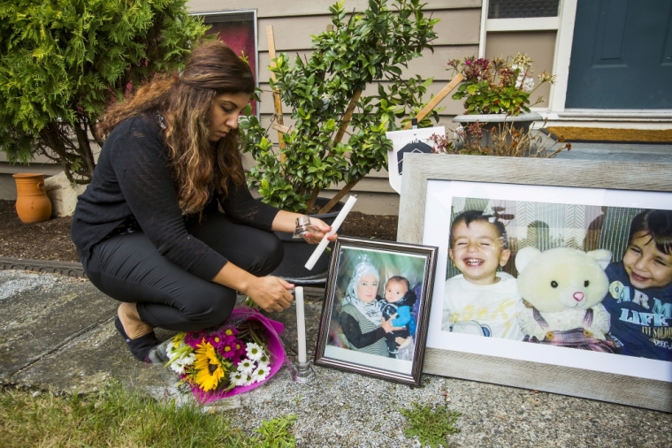 Nissy Koye, friend of Tima Kurdi, the sister of Syrian refugee Abdullah Kurdi whose sons Aylan and Galip and wife Rehan were among 12 people who drowned in Turkey trying to reach Greece, lights a candle near photographs of the boys outside Tima's home in Coquitlam, British Columbia, September 3, 2015. A photograph of the tiny body of 3-year old Aylan Kurdi washed up in the Aegean resort of Bodrum swept social media on Wednesday and featured on front pages on Thursday, spawning sympathy and outrage at the perceived inaction of developed nations in helping refugees.