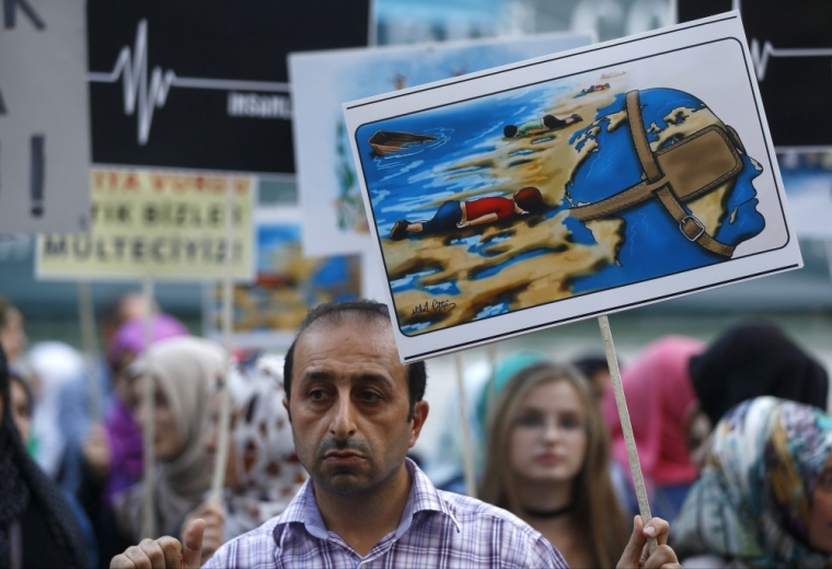 A man holds a poster with a drawing depicting drowned Syrian toddlers during a demonstration for refugee rights in Istanbul, Turkey, September 3, 2015. The distraught father of two Syrian toddlers who drowned with their mother and several other migrants as they tried to reach Greece identified their bodies on Thursday and prepared to take them back to their home town of Kobani. Abdullah Kurdi collapsed in tears after emerging from a morgue in the city of Mugla near Bodrum, where the body of his three-year old son Aylan washed up on Wednesday. The image of Aylan, drowned off one of Turkey's most popular holiday resorts, went viral on social media and piled pressure on European leaders. Abdullah's family had been trying to emigrate to Canada after fleeing the war-torn town of Kobani, a revelation which also put Canada's Conservative government under fire from its political opponents.