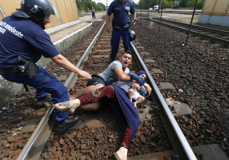 Hungarian policemen stand by the family of migrants as they wanted to run away at the railway station in the town of Bicske, Hungary, September 3, 2015. A camp for refugees and asylum seekers is located in Bicske.