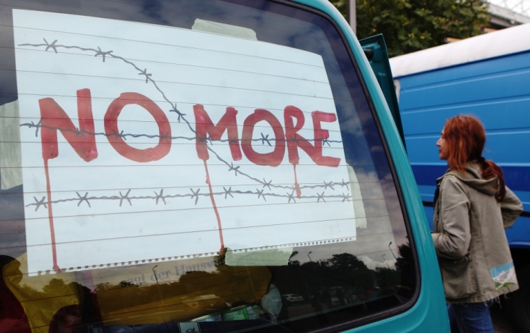 An activist walks past a car taking part in a convoy of around 140 vehicles leaving for Hungary from Vienna, September 6, 2015, to distribute aid to migrants and to collect refugees to bring back to Austria. People taking part run the risk of violating laws on human trafficking, police said, but officers were there at the meeting point outside a football stadium just to provide security and guide traffic.