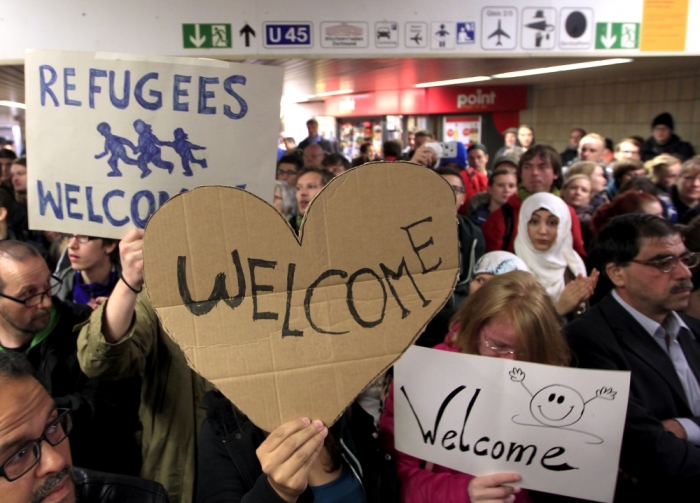 Wellwishers wave to migrants arriving at the main railway station in Dortmund, Germany September 6, 2015. Austria and Germany threw open their borders to thousands of exhausted migrants on Saturday, bussed to the Hungarian border by a right-wing government that had tried to stop them but was overwhelmed by the sheer numbers reaching Europe's frontiers.