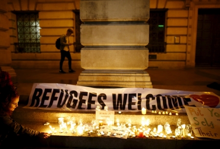 A woman lights a candle during a vigil for refugees in Nottingham, Britain, September 7, 2015. British Prime Minister David Cameron pledged on Monday to take in up to 20,000 refugees from camps in Syria over the next five years, responding to public pressure to help.