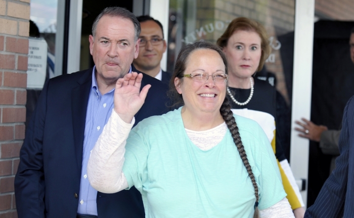 Kim Davis, flanked by Republic presidential candidate Mike Huckabee (L) waves as she walks out of jail in Grayson, Kentucky September 8, 2015. U.S. District Judge David Bunning ordered her release after six days in jail, saying she 'shall not interfere in any way, directly or indirectly, with the efforts of her deputy clerks to issue marriage licenses to all legally eligible couples.'