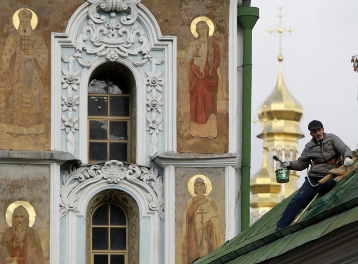 A worker paints the roof of a building in front of Kievo-Pecherskaya Lavra Cathedral in Kiev, Ukraine, October 11, 2012.