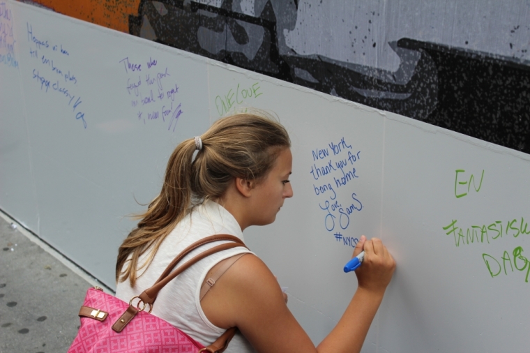 A woman writes on a memorial wall in lower Manhattan, New York City, in honor of the fallen on the 14th anniversary of the 9/11 attacks on September 11, 2015.