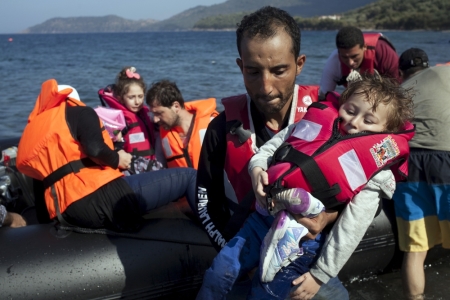 A Syrian refugee holds a baby moments after arriving on a dinghy on the Greek island of Lesbos, September 11, 2015. A refugee bottleneck on Greece's easternmost islands has eased after recent dangerous overcrowding, rescue agencies said on Friday, as thousands of migrants per day continue to arrive on the mainland.