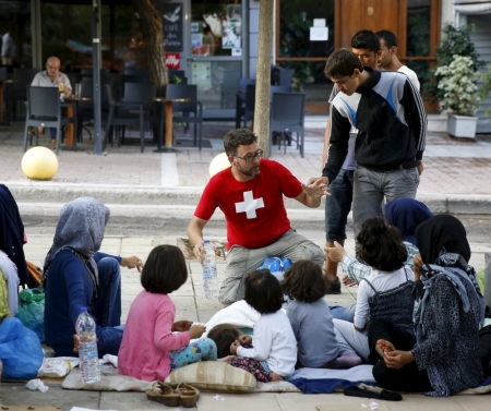 A man hands out water to Afghan refugees in Victoria Square at the center of Athens, Greece, September 11, 2015. Some 7,600 migrants, many of them refugees from the Syrian war, entered Macedonia from Greece between 6 p.m. (1600 GMT) on Wednesday and 6 p.m. on Thursday, an official with the United Nations refugee agency said on the border. Migrants are flowing in increasing numbers through the Balkan peninsula towards Hungary as Greece ferries them from inundated islands to Athens, from where they head north to Macedonia.