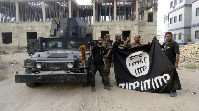 Iraqi security forces hold an Islamist State flag which they pulled down at the University of Anbar, in Anbar province July 26, 2015. Iraqi security forces entered the University of Anbar in the western city of Ramadi on Sunday and clashed with Islamic State militants inside the compound, the joint operations command said in a statement.