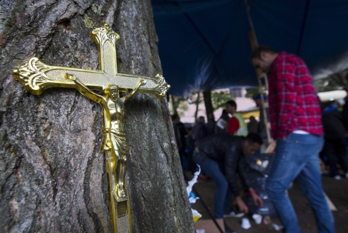 A crucifix hangs from a tree at a makeshift camp during a day of solidarity organized by local organizations and residents for asylum seekers and migrants at a makeshift camp outside the foreign office in Brussels, Belgium, September 6, 2015.
