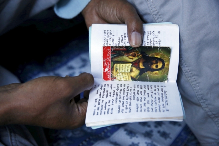 Christian migrants from Eritrea and Ethiopia pray and read the bible before Sunday mass at the makeshift church in 'The New Jungle' near Calais, France, August 2, 2015.