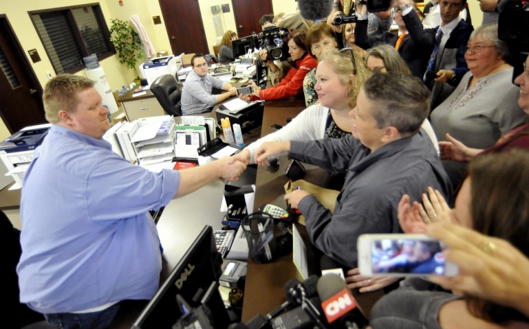 Deputy clerk Brian Mason (L) shakes hands with Carmen and Shannon Wampler-Collins after issuing them a marriage license at Rowan County Clerk's Office in Morehead, Kentucky, September 14, 2015. Kim Davis, who was jailed after refusing to issue marriage licenses to gay couples, said Monday she will not authorize the licenses now that she has returned to work, but she will not block her deputies from issuing them.