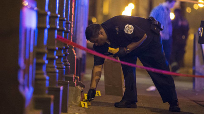 A Chicago police officer collects evidence at a crime scene where a man was shot in the city in this July 5, 2015, photo.