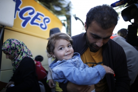 A young girl is carried by his father as refugees from Syria and Irak disembark from a coach at a refugee centre in Champagne-sur-Seine, near Paris, France, September 9, 2015. France is ready to take in 24,000 refugees as part of European Union plans to welcome more than 100,000 in the next two years, the French President said on Monday, dismissing opinion polls showing public opposition to the move.