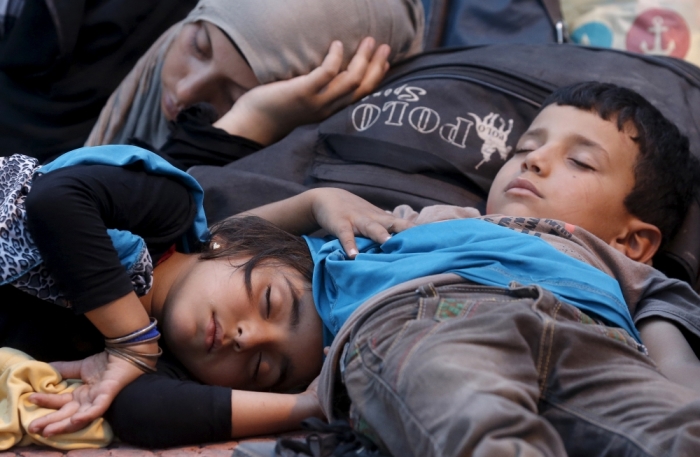 Refugees and migrants rest after disembarking from a Greek ferry arriving from the island of Kos in the port of Piraeus near Athens, Greece, August 15, 2015. United Nations refugee agency called on Greece to take control of the 'total chaos' on Mediterranean islands, where thousands of migrants have landed. About 124,000 have arrived this year by sea, many via Turkey, according to Vincent Cochetel, UNHCR director for Europe.