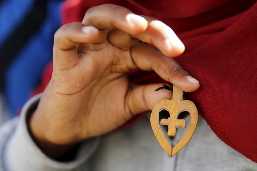 A Christian migrant from Eritrea shows a crucifix made of wood after she attended a Sunday mass at the makeshift church in 