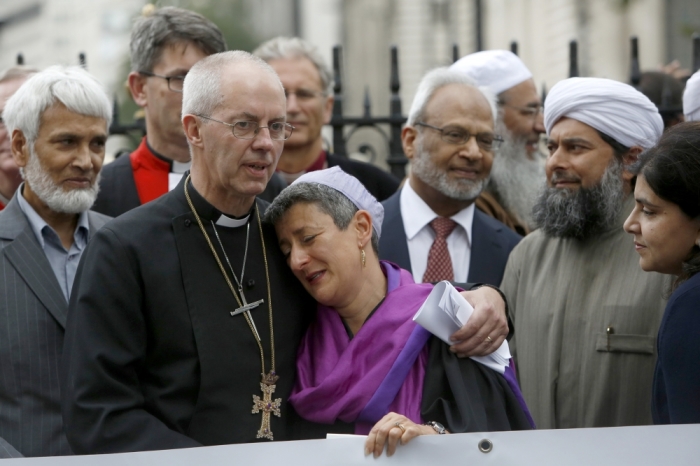 The Archbishop of Canterbury, Justin Welby (2L), Senior Rabbi Laura Janner-Klausner (C), Imam Shaykh Ibrahim Mogra (2R) and Sayeeda Warsi (R) react together at the close of a vigil outside Westminster Abbey in central London September 3, 2014.