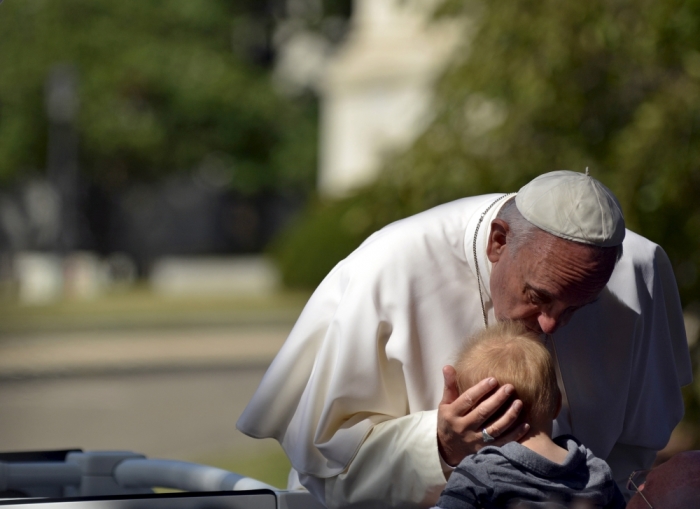 Pope Francis kisses a baby as he parades around the White House Ellipse in Washington, September 23, 2015.