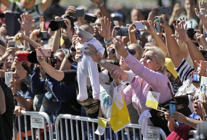 A baby is held up and as a crowd reactsduring a papal parade in Washington, September 23, 2015. Pope Francis is making his first visit to the United States.
