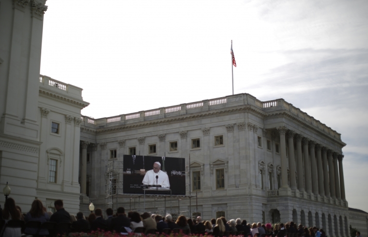 Spectators watch Pope Francis on a video screen outside the West Front of the U.S. Capitol as he addresses a joint meeting of the U.S. Congress on Capitol Hill in Washington September 24, 2015.