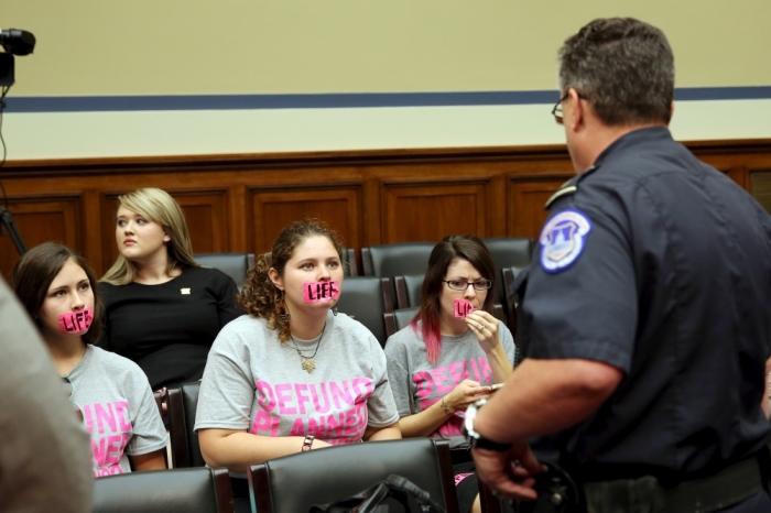 Three anti-abortion protestors are given direction by a Capitol Hill policeman (R) on behavior before Planned Parenthood Federation president Cecile Richards (not pictured) testifies at the House Committee on Oversight and Government Reform on Capitol Hill in Washington September 29, 2015.