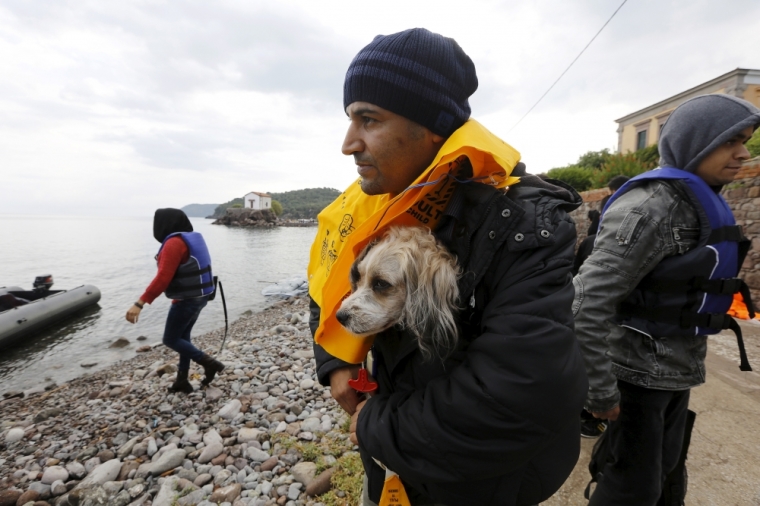 An exhausted Afghan migrant carries his dog in his life vest moments after arriving to the Greek island of Lesbos in an overcrowded dinghy, after crossing a part of the Aegean Sea from Turkey to Lesbos, September 24, 2015.