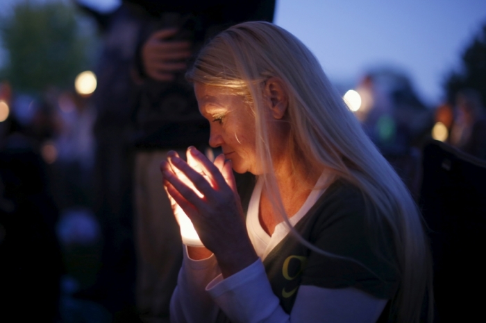 A woman takes part in a candlelight vigil for victims of the Umpqua Community College shooting, in Winston, Oregon, United States, October 3, 2015. The gunman who killed his English professor and eight others at an Oregon community college committed suicide after a shootout with police who were on the scene within five minutes and exchanged fire with him almost immediately, authorities said.