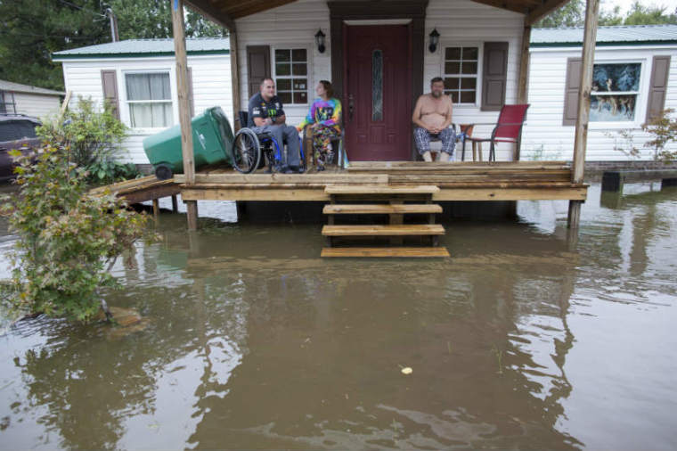 Chris Stumbo (L-R), his girlfriend Felicia Howerton and Paul Stumbo check out the level of flood waters surrounding their home on Applewood Court in Myrtle Beach, South Carolina October 5, 2015.